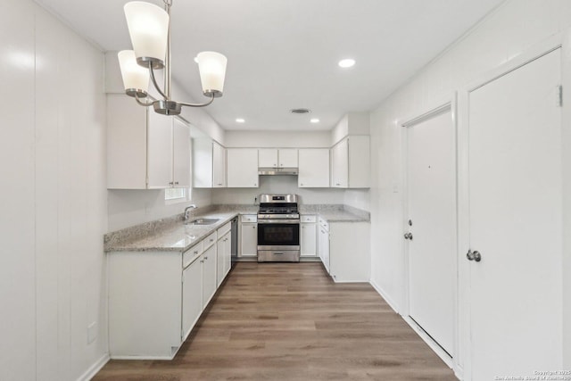 kitchen featuring light wood finished floors, recessed lighting, appliances with stainless steel finishes, white cabinets, and a sink