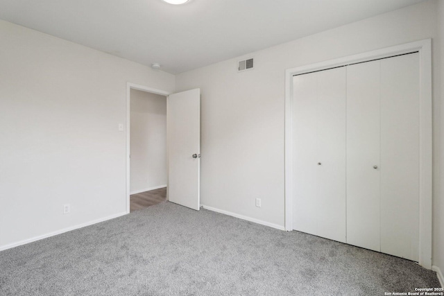 unfurnished bedroom with carpet, a closet, visible vents, and baseboards