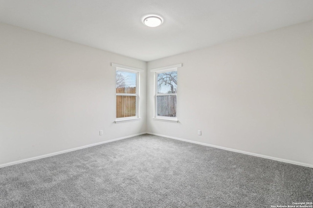 unfurnished room featuring carpet and baseboards