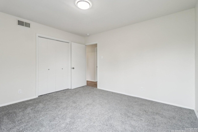 unfurnished bedroom with carpet floors, baseboards, visible vents, and a closet