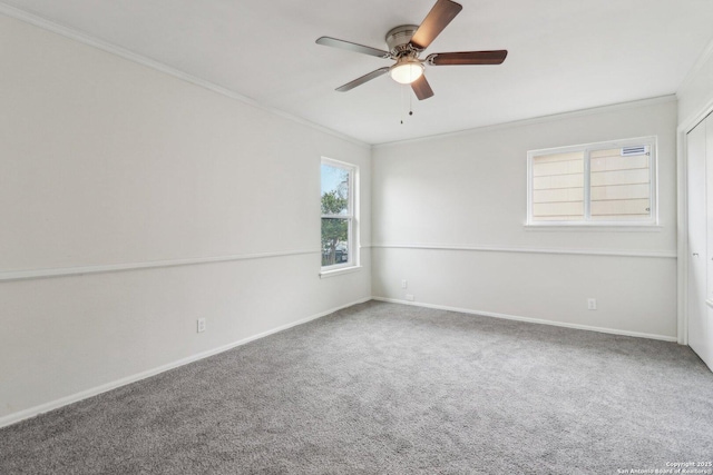 carpeted spare room with ceiling fan, ornamental molding, and baseboards