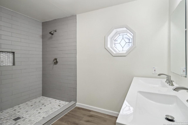 bathroom with a shower stall, baseboards, a sink, and wood finished floors