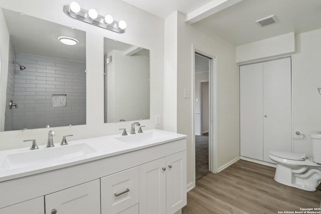 bathroom featuring toilet, double vanity, a sink, and visible vents