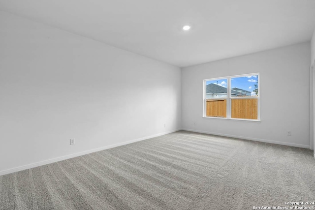 empty room featuring light carpet, recessed lighting, and baseboards