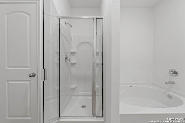 bathroom featuring a garden tub and a shower stall