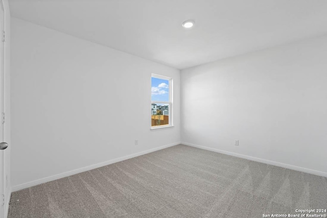 unfurnished room with carpet flooring and baseboards