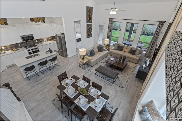 living room featuring light wood finished floors, a high ceiling, and a ceiling fan