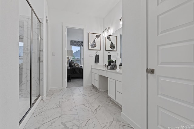 ensuite bathroom featuring marble finish floor, a marble finish shower, vanity, ensuite bath, and baseboards