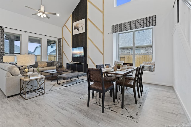 dining room with light wood-type flooring, a wealth of natural light, and a high ceiling