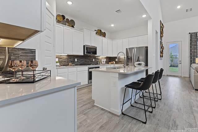 kitchen with a kitchen bar, white cabinetry, stainless steel appliances, and a sink