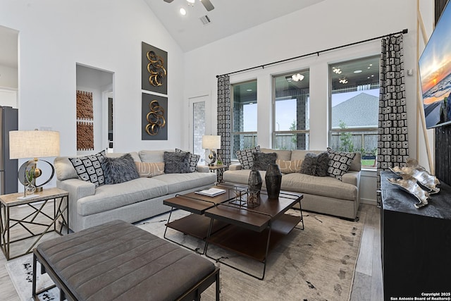 living area featuring high vaulted ceiling, visible vents, ceiling fan, and light wood-style flooring