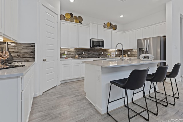 kitchen with a kitchen bar, white cabinetry, stainless steel appliances, and a sink