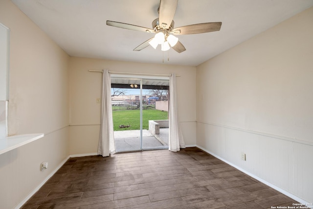 spare room featuring ceiling fan, dark wood-style flooring, and wainscoting