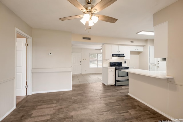 kitchen with dark wood finished floors, stainless steel electric range, light countertops, under cabinet range hood, and white cabinetry