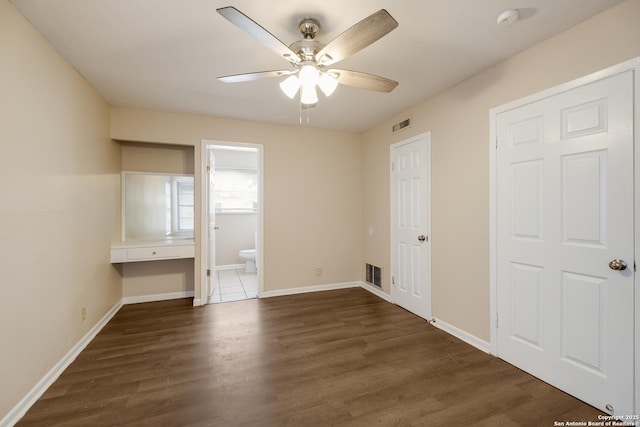 unfurnished bedroom featuring visible vents, dark wood finished floors, ensuite bath, and baseboards