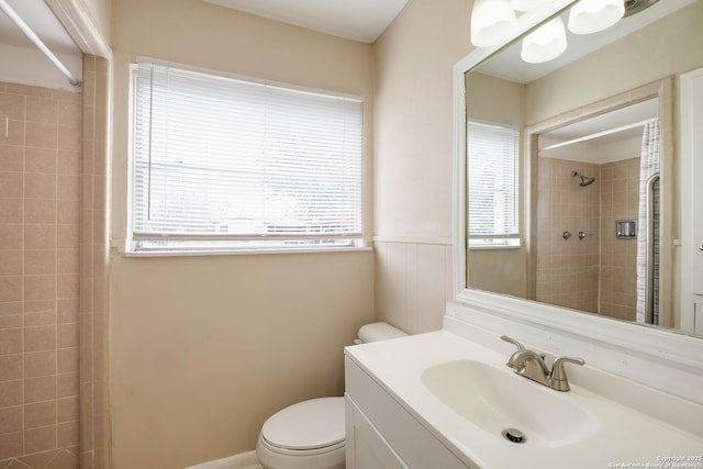 full bathroom featuring tiled shower, vanity, and toilet