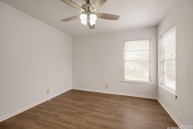 unfurnished room with dark wood finished floors, a ceiling fan, and baseboards