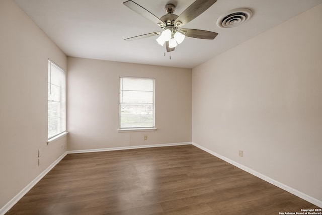 unfurnished room with baseboards, visible vents, dark wood finished floors, and a ceiling fan