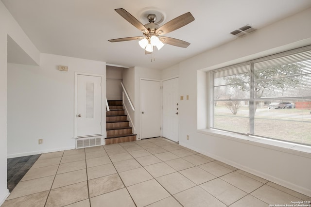 unfurnished room featuring light tile patterned floors, stairs, visible vents, and a ceiling fan