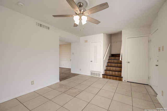 empty room with light tile patterned floors, stairway, visible vents, and a ceiling fan