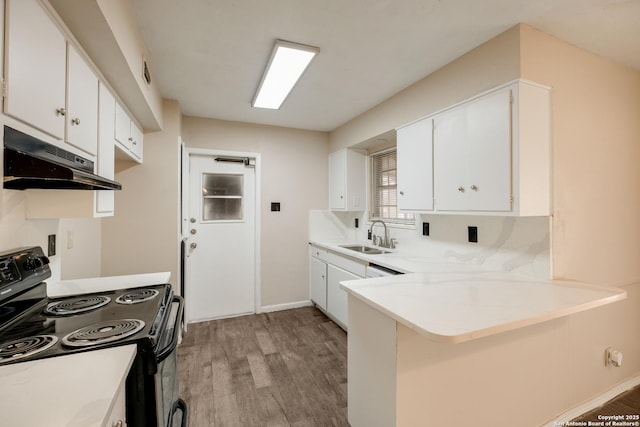 kitchen with under cabinet range hood, a peninsula, electric range, white cabinetry, and light countertops