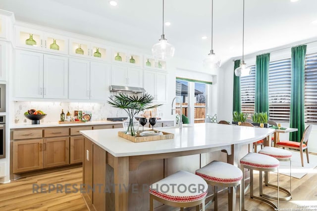 11717 Warlock, San Antonio, TX 78254 - kitchen with light wood-style flooring, light countertops, a breakfast bar area, backsplash, and recessed lighting