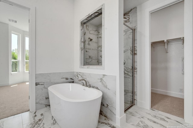 11717 Warlock, San Antonio, TX 78254 - full bath featuring marble look tiles, a soaking tub, a marble finish shower, a spacious closet, and a wainscoted wall