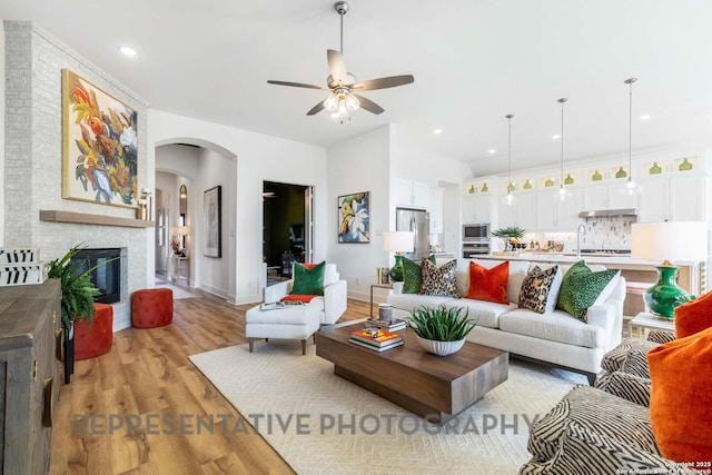 11717 Warlock, San Antonio, TX 78254 - living area with a ceiling fan, arched walkways, light wood-type flooring, a brick fireplace, and recessed lighting
