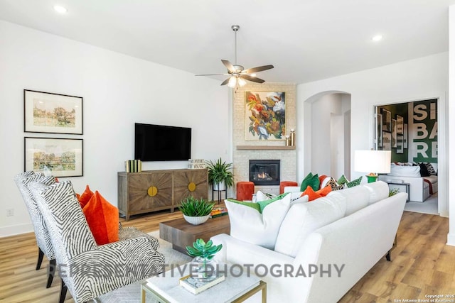 11717 Warlock, San Antonio, TX 78254 - living area with arched walkways, ceiling fan, light wood-style floors, a fireplace, and recessed lighting