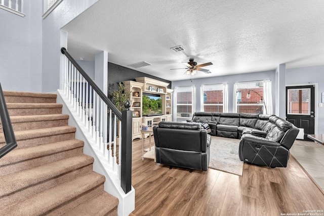 living area with visible vents, stairway, a textured ceiling, and wood finished floors