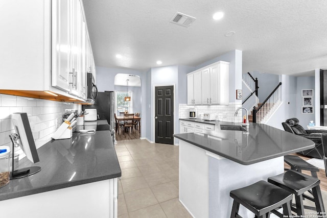 kitchen with visible vents, black microwave, a sink, and white cabinetry