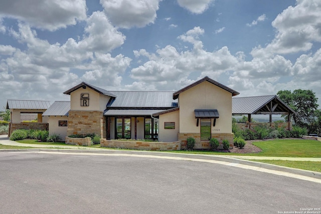 view of front facade featuring stone siding, a standing seam roof, metal roof, and stucco siding