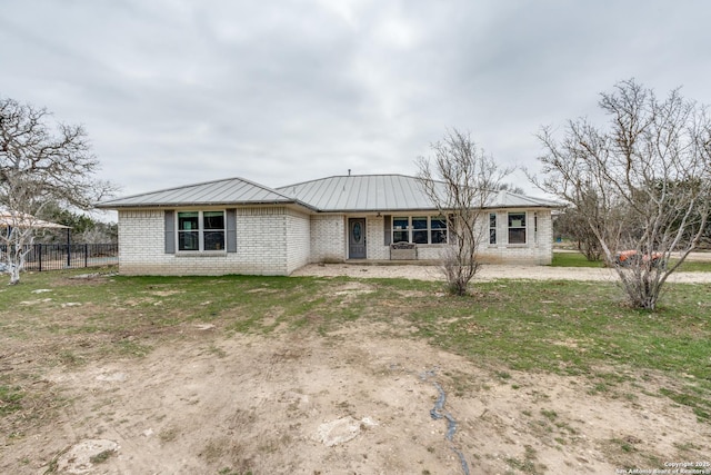 ranch-style house featuring metal roof, brick siding, a standing seam roof, and fence