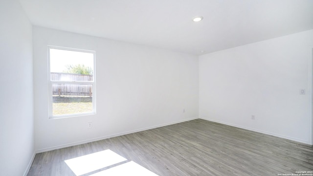 empty room with recessed lighting, baseboards, and wood finished floors