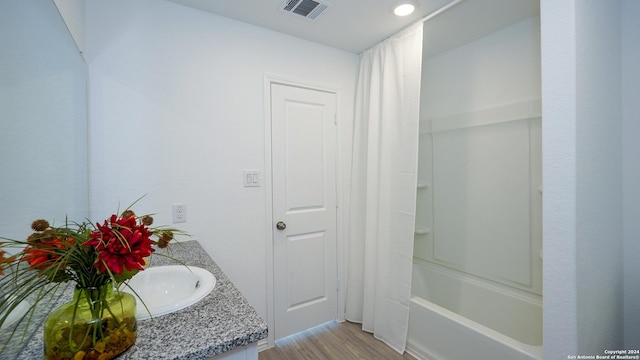 full bathroom with shower / bath combo, visible vents, wood finished floors, and vanity