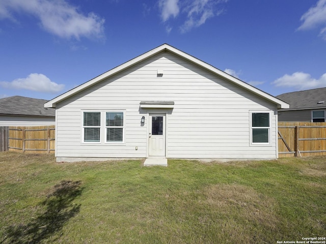 back of property featuring a yard and fence