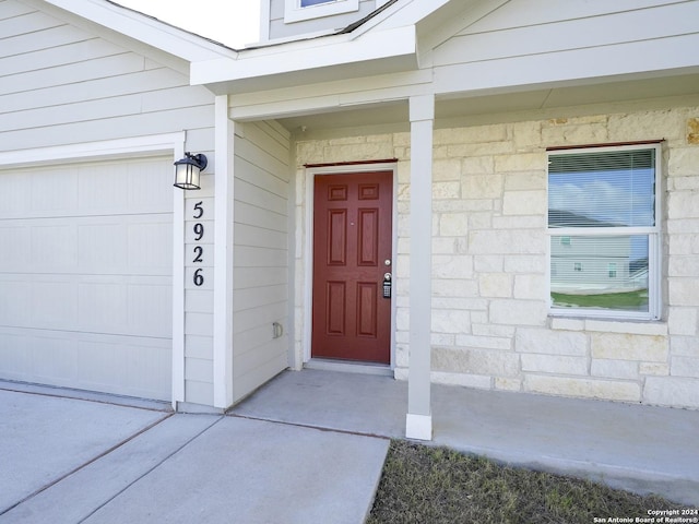 property entrance with a garage and stone siding