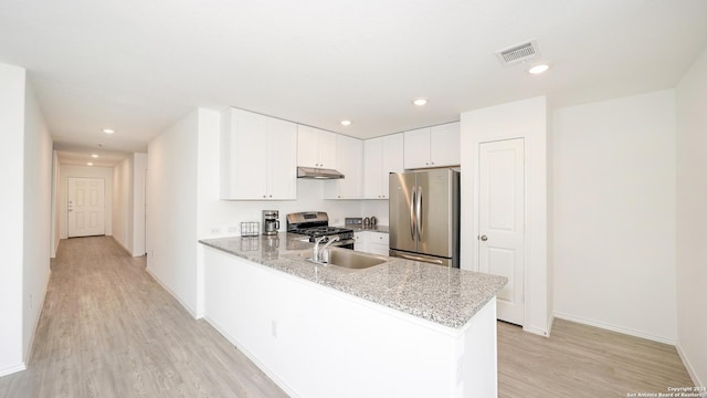 kitchen with light stone counters, appliances with stainless steel finishes, white cabinets, a peninsula, and under cabinet range hood