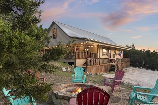 exterior space with a porch, an outdoor fire pit, a patio area, metal roof, and stairs