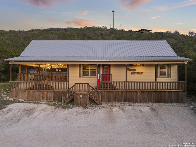 view of front of house featuring a porch, metal roof, and stairs