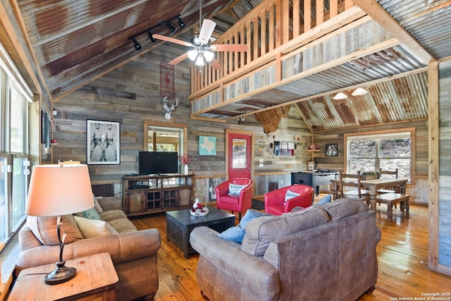 living area featuring high vaulted ceiling, beamed ceiling, wood walls, and wood finished floors