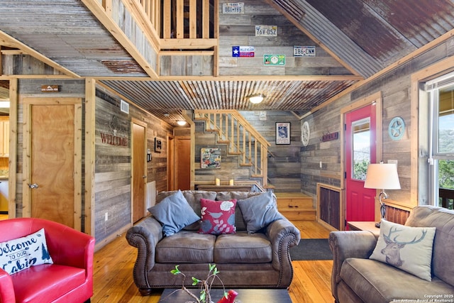 living room with wooden ceiling, wood walls, stairway, and wood finished floors