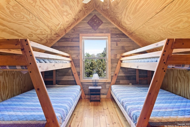 bedroom featuring wooden ceiling, vaulted ceiling, wooden walls, and wood finished floors