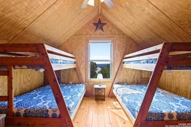 bedroom featuring vaulted ceiling, wooden walls, and wood finished floors