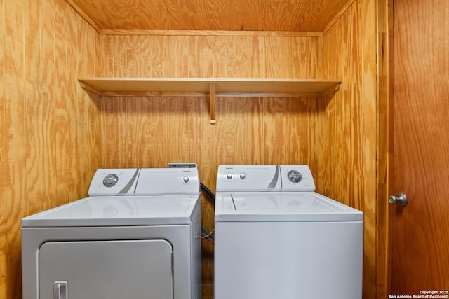 washroom with washer and dryer, laundry area, and wood walls