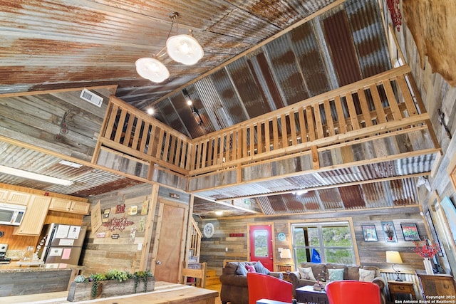 interior space featuring a towering ceiling, wooden ceiling, wooden walls, and visible vents