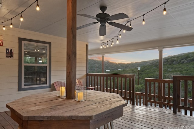 wooden deck with outdoor dining space and a ceiling fan