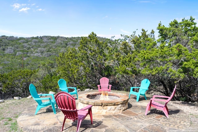 view of patio featuring a fire pit and a view of trees