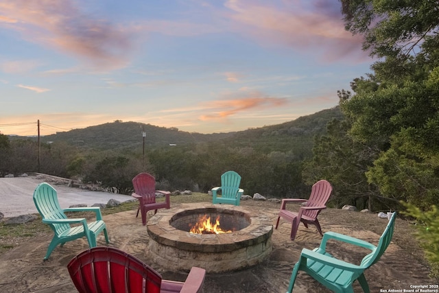 patio terrace at dusk with a fire pit and a mountain view