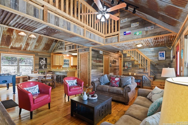 living area featuring wood walls, stairs, high vaulted ceiling, and wood finished floors